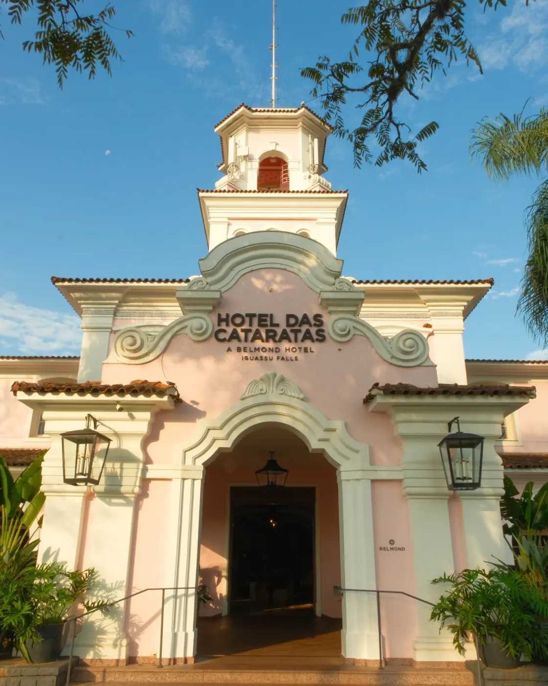 Pink impatiens in front of the arcaded pink facade and tower of Belmond Hotel das Cataratas